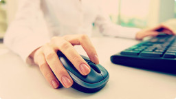 Close up of a hand using a computer mouse and keyboard